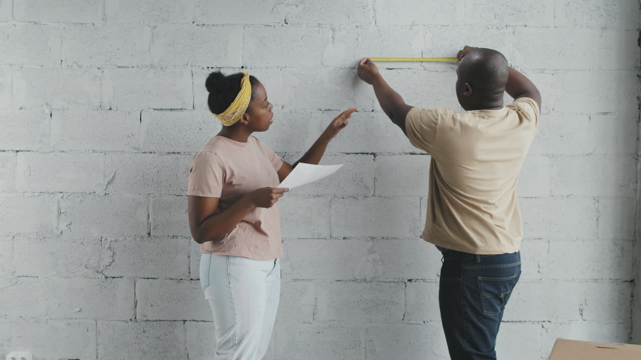 Couple measuring wall for home improvement project