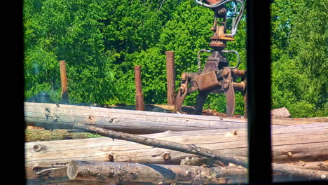 large log truck unloading timber from trailer seen from sawmill window