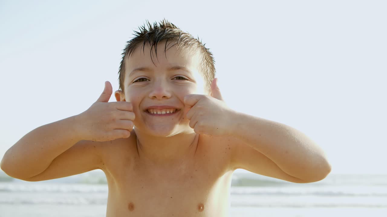 해변에서 카메라에 미소 짓는 행복한 작은 소년