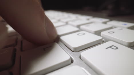 Man-types-on-computer-keyboard-at-table-on-black-background