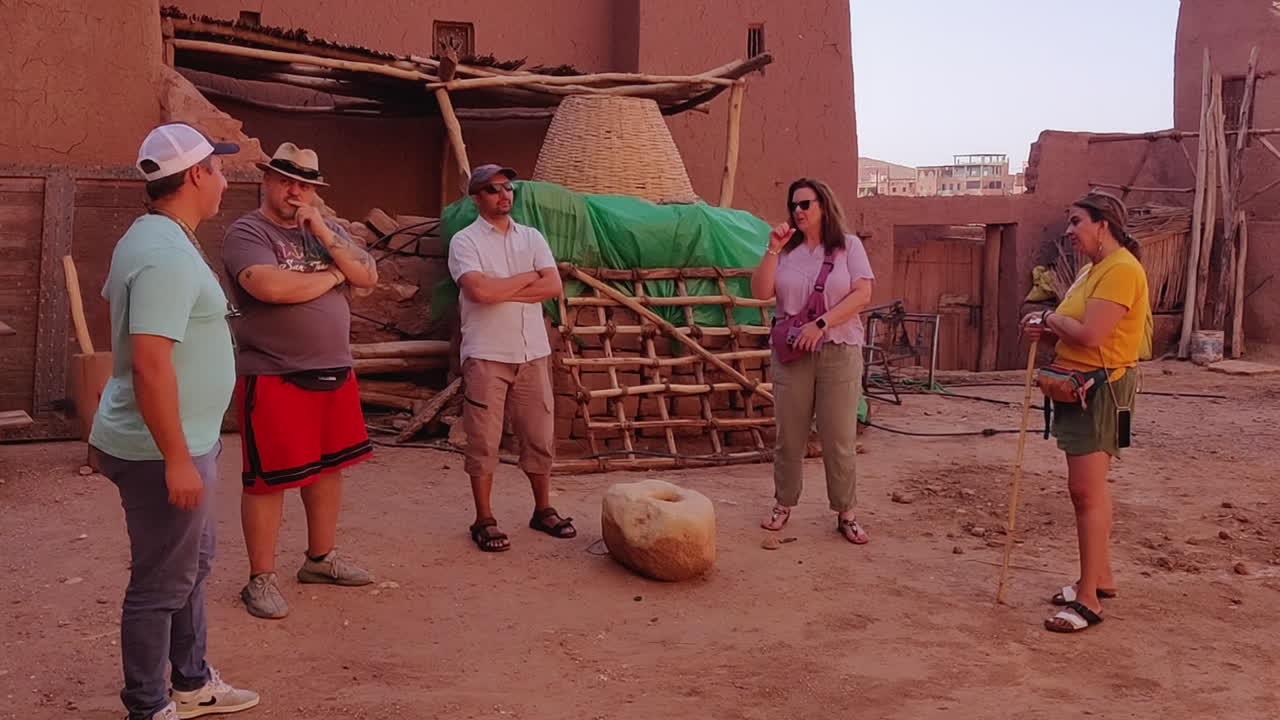 Tour Guide Talking With Group Of Tourists At Kasbah Of Ait Benhaddou In Morocco. wide shot