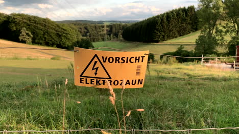 Caution-sign-on-wire-fence-on-sunny-summer-day-in-Germany