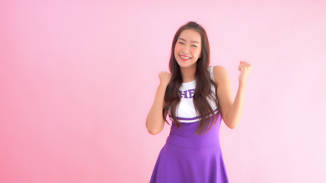 A cheerleader expresses her enthusiasm with fist pumps and smiles. Copy space