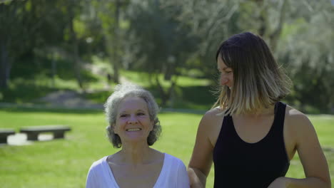 Two-smiling-women-jogging-in-park,-laughing,-enjoying-sunny-day