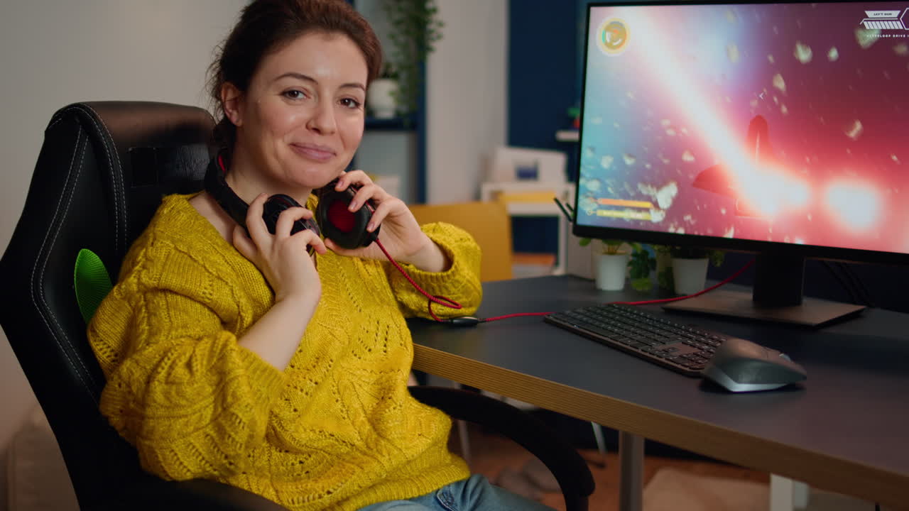 Woman gamer taking off headseat looking at camera smiling