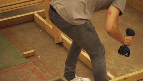 young man checking stability of wood after drilling hole in diy workshop project