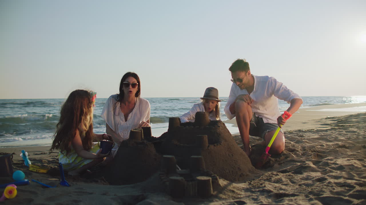 한 가족 이 해변 에 모래 성 을 짓고 있다