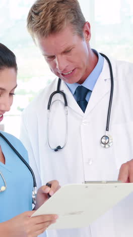 doctor looking at clipboard with nurse