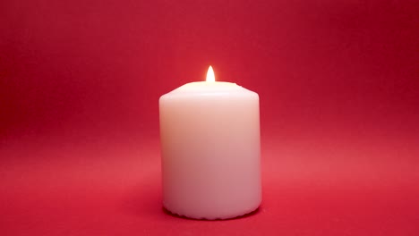 lighting white candle with match, illuminated red background in studio