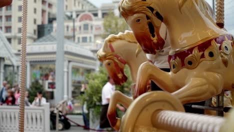 pov from carousel to city. horses close up and down. happy kids with parents riding carousel and taking pictures and selfies. merry-go-round carousel