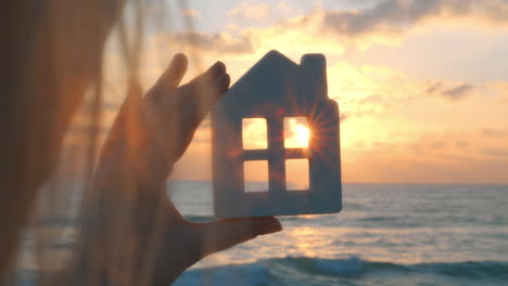 crop woman looking at sunset through toy house