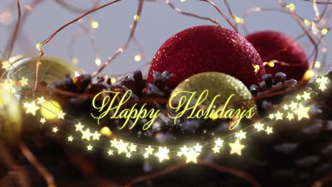Animation-of-text,-happy-holidays,-in-yellow,-over-string-lights-and-christmas-decorations