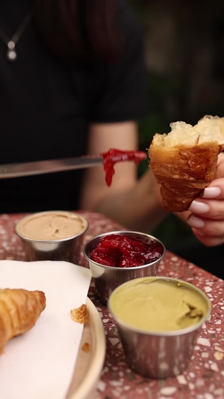 Spreading Strawberry Jam on a Fresh Croissant for Breakfast