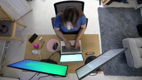 overhead view of a woman working remotely at a multi-screen home office setup
