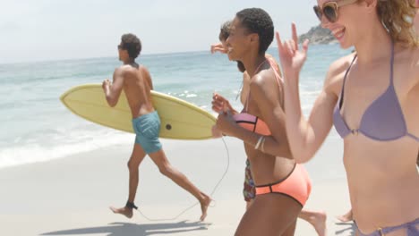 Side-view-of-mixed-race-friends-running-together-on-the-beach-4k