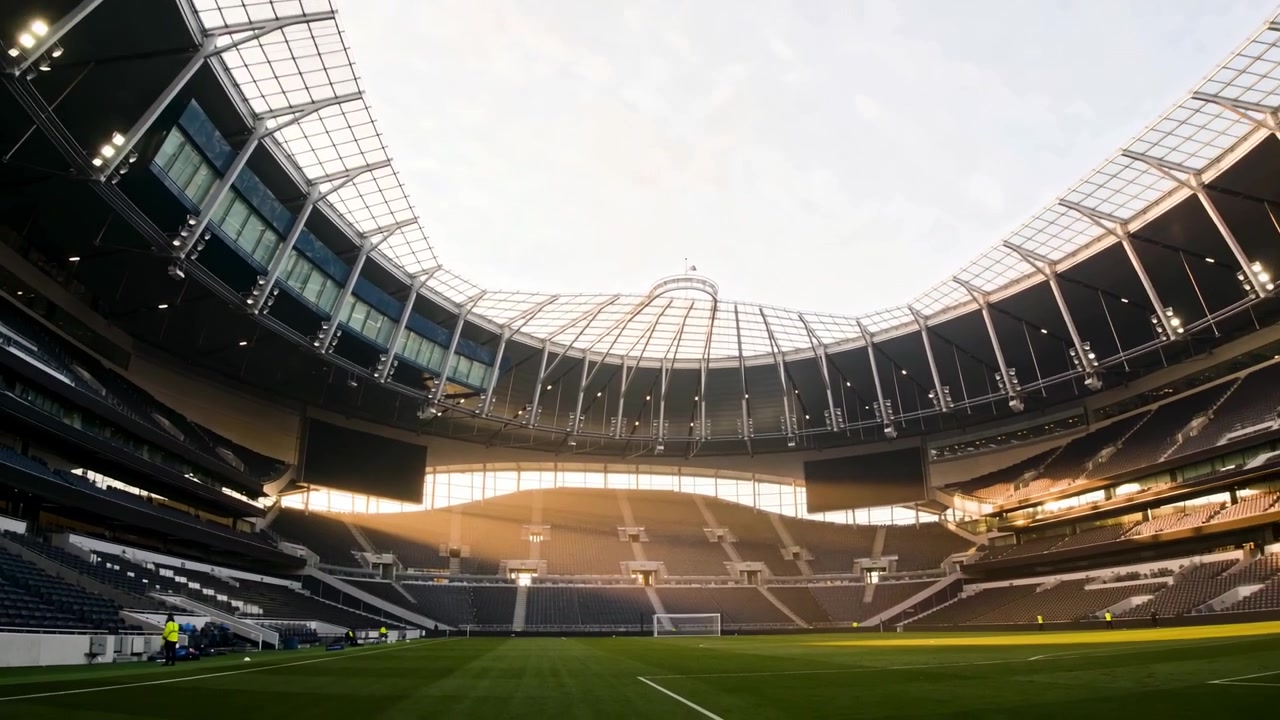 Il sole che illumina, telecamera che si inclina sopra il tetto a conca dello stadio, personale con giubbotti ad alta visibilità che controlla la porta.
