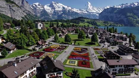 aerial video captures a vibrant village with colorful gardens, nestled between lush hills