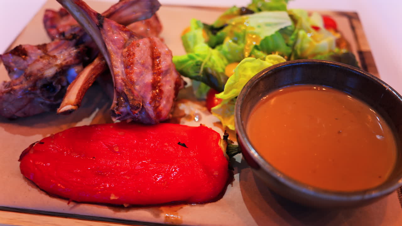 Close up of lamb chops with sauce and a side salad on a plate at a restaurant