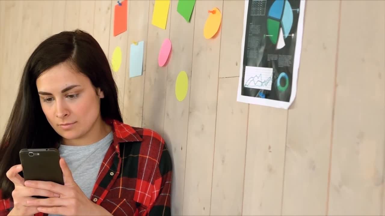 ejecutivo de negocios usando el teléfono móvil mientras se apoya en la pared