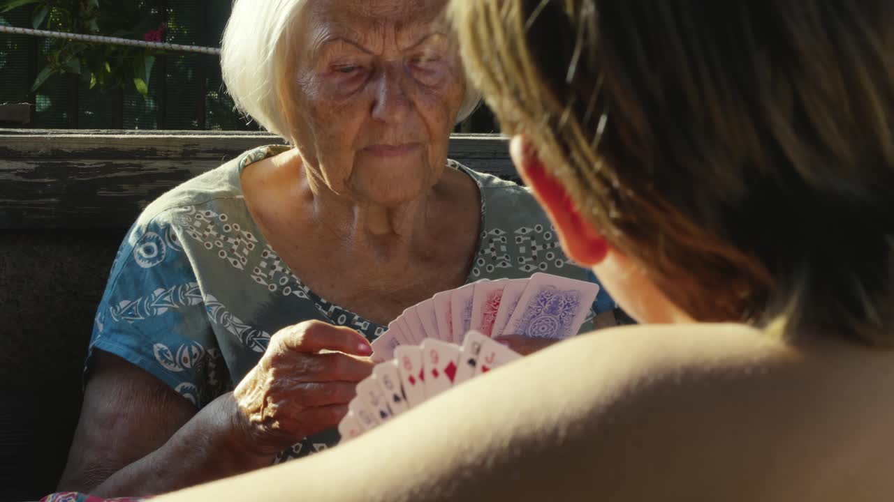 Happy Children play family fun card game with Grandma in sunny garden