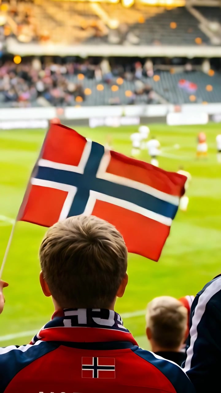 Vertikal video: Barn med Norge-skjerf ser spillere bevege seg på banen på stadion, flagg vaier