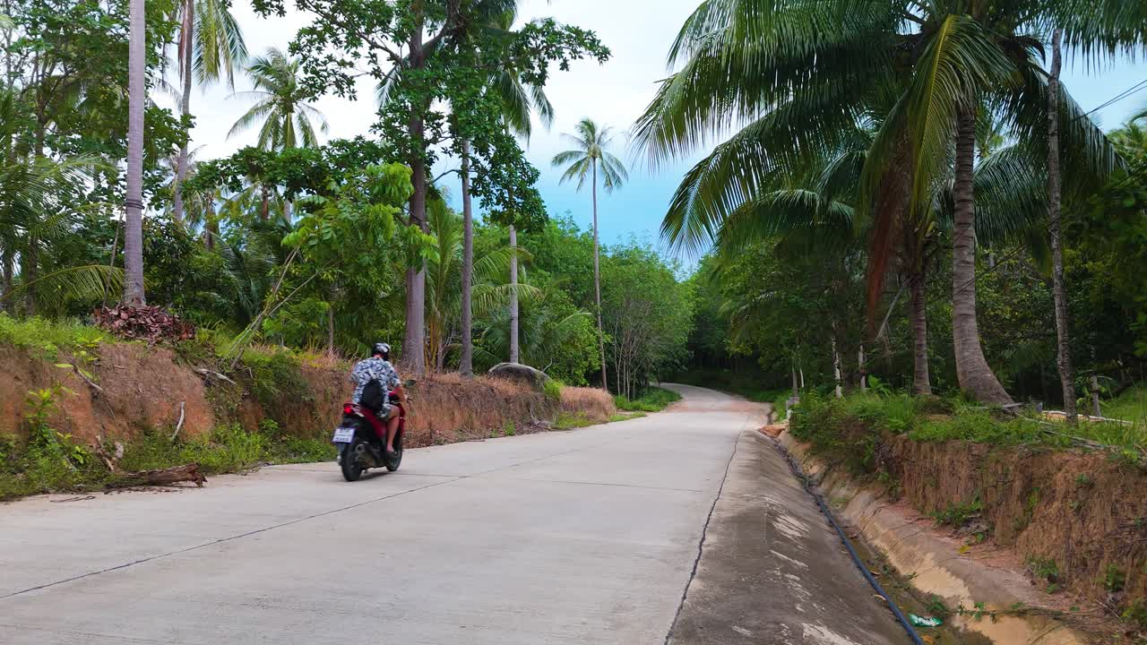 tourist on bright red moped driving by, static view of thailand road, tourist thailand roadtrip in Ko Pha Ngan island peaceful scenery showing the holiday feeling