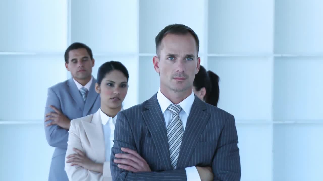 un hombre de negocios liderando a su equipo con los brazos cruzados.