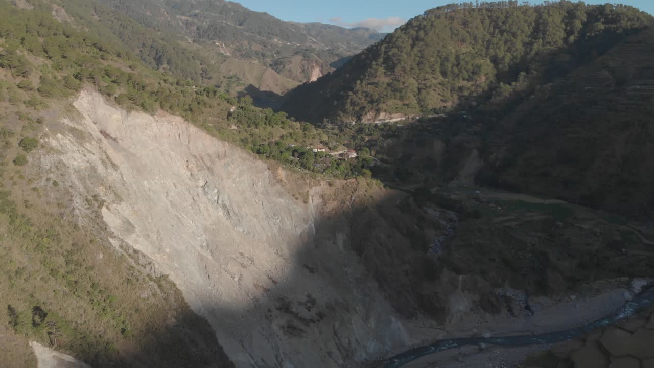Aerial reversing and revealing a giant rock wall carved out by a river rock slide in a moutainous region of Kabayan, Benguet, Pilippines