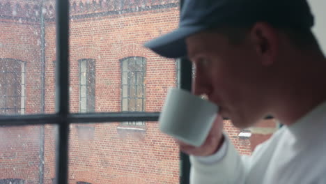 young man enjoying a warm drink by the window on a snowy day