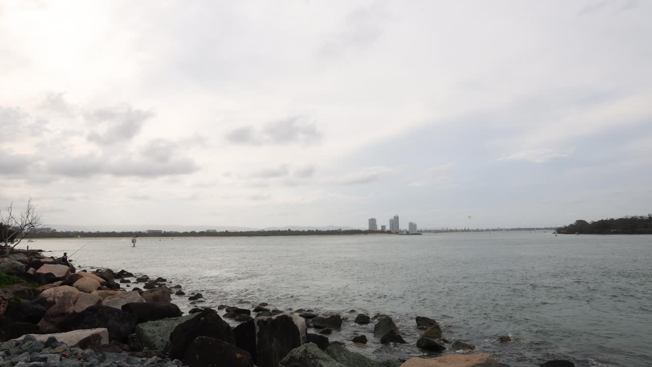 먼 곳 에 도시 의 스카이 라인 이 있는 바위 가 있는 해안