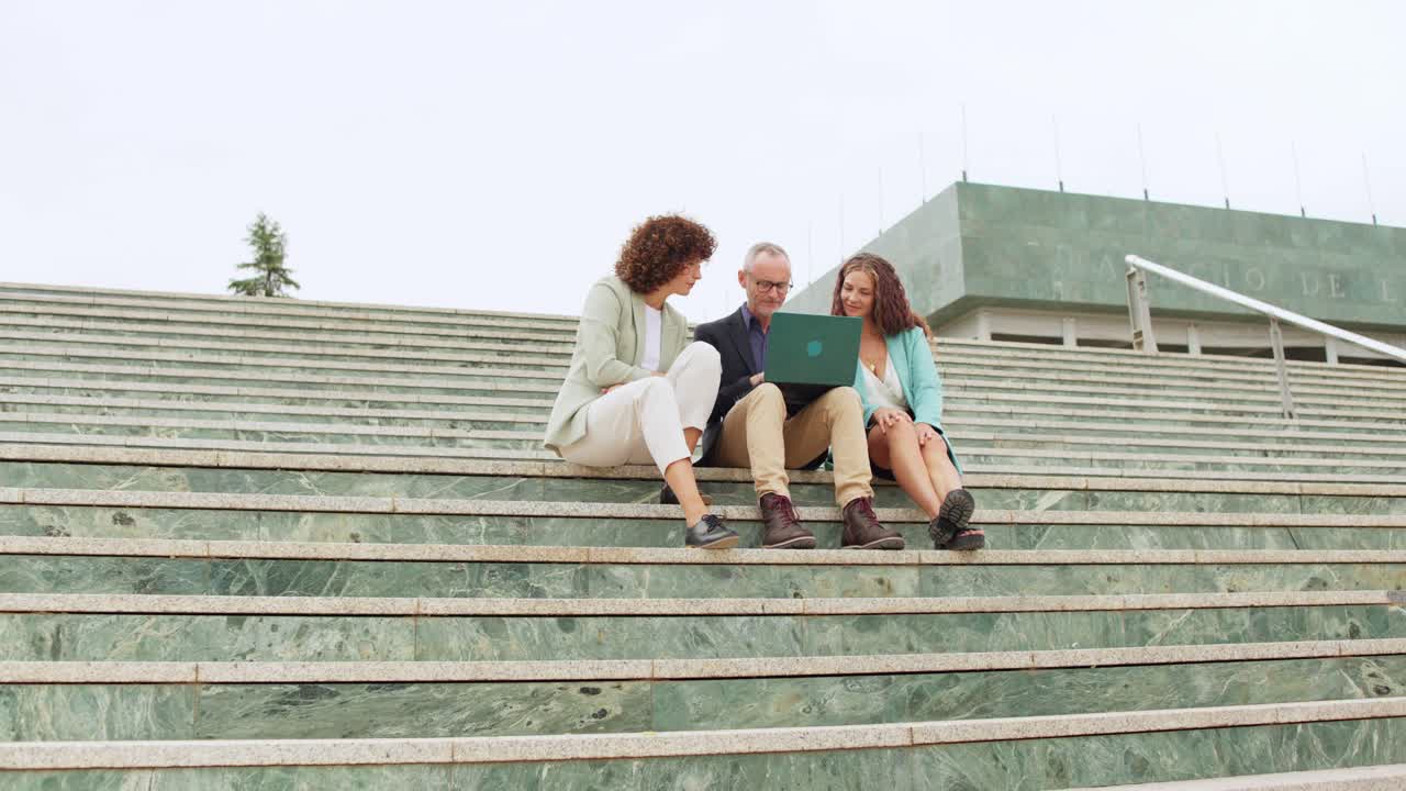 Group of people sitting on stairs using laptop