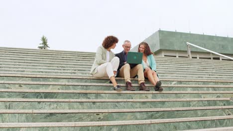 Group of people sitting on stairs using laptop