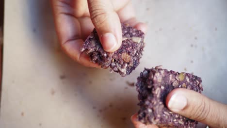 close up of a person's hand breaking a purple granola bar