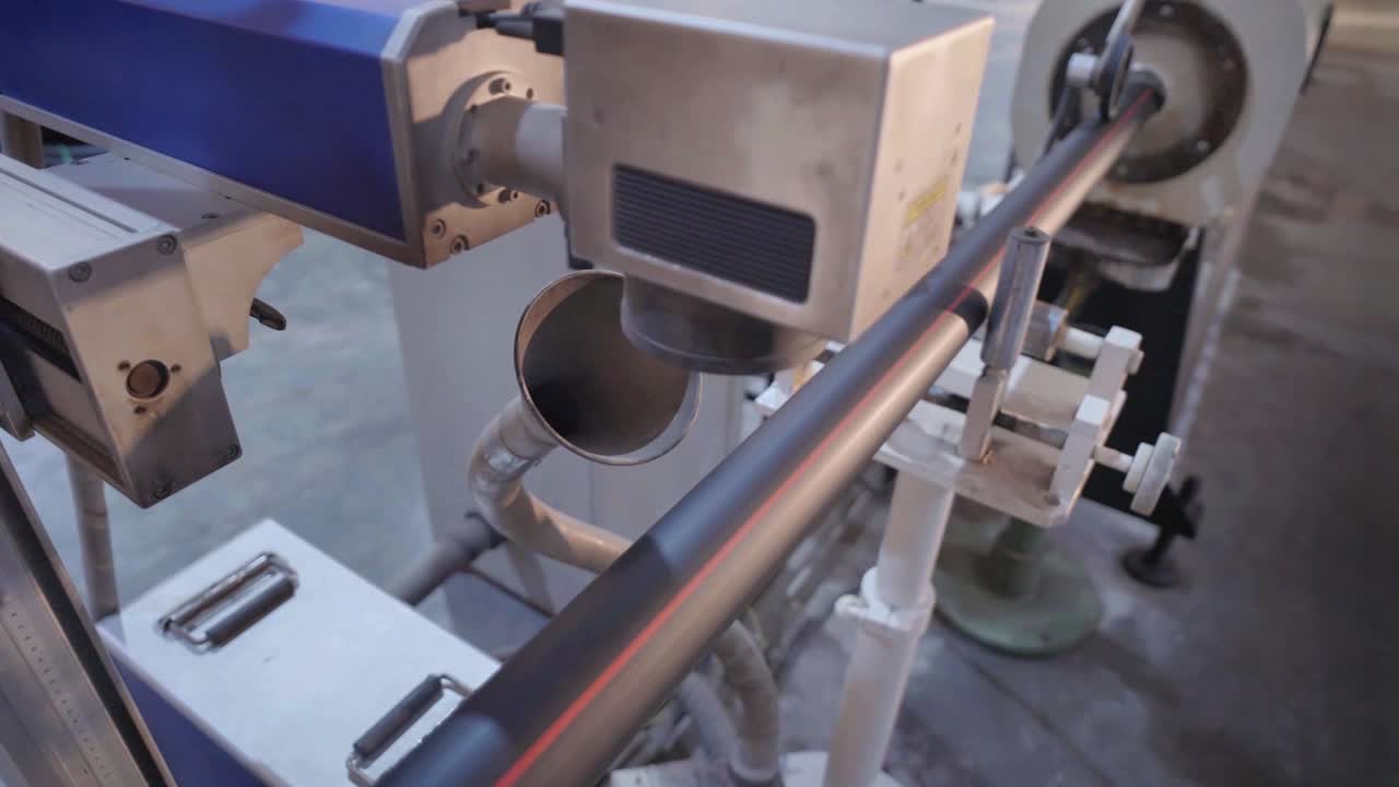 Close-up view of industrial machinery working on a metal pipe, highlighting the precise cutting and shaping process in a modern manufacturing facility.