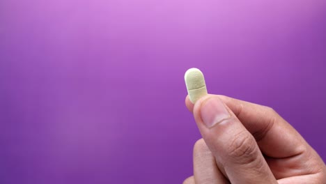 hand holding a light yellow oval pill