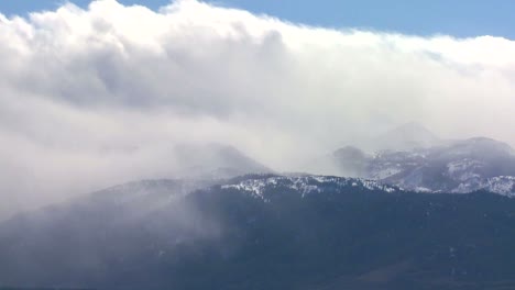 clouds blow over the top of an alpine mountain range in winter