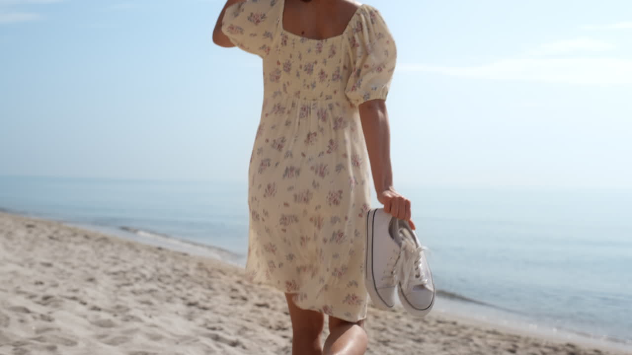 элегантная девушка бежит по песчаному пляжу в соломенной шляпе. женщина ходит босиком.