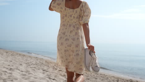 elegant girl running sand beach in straw hat back view. woman walking barefoot.