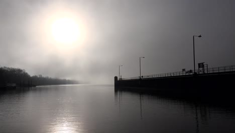 sun rises on a foggy morning along the locks of the mississippi river