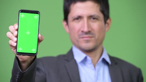 Happy Hispanic businessman showing phone