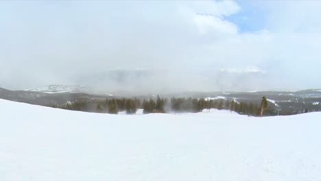 Snow-blowing-across-an-empty-ski-run-in-the-mountains-on-an-overcast-day,-handheld