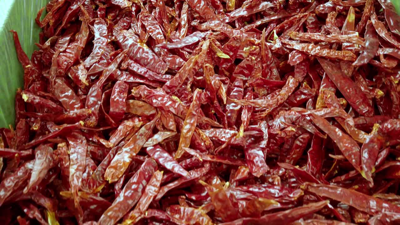 Pan shot of crushed guajillo chili in a big basket during the day, handheld shot