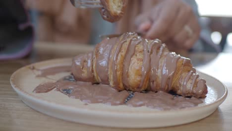 person eating a chocolate croissant