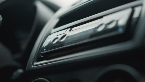 down view of male hands tuning music player knob on car console interior focusing on finger gesture ambient lighting dashboard buttons during winter drive preparation capturing audio interaction