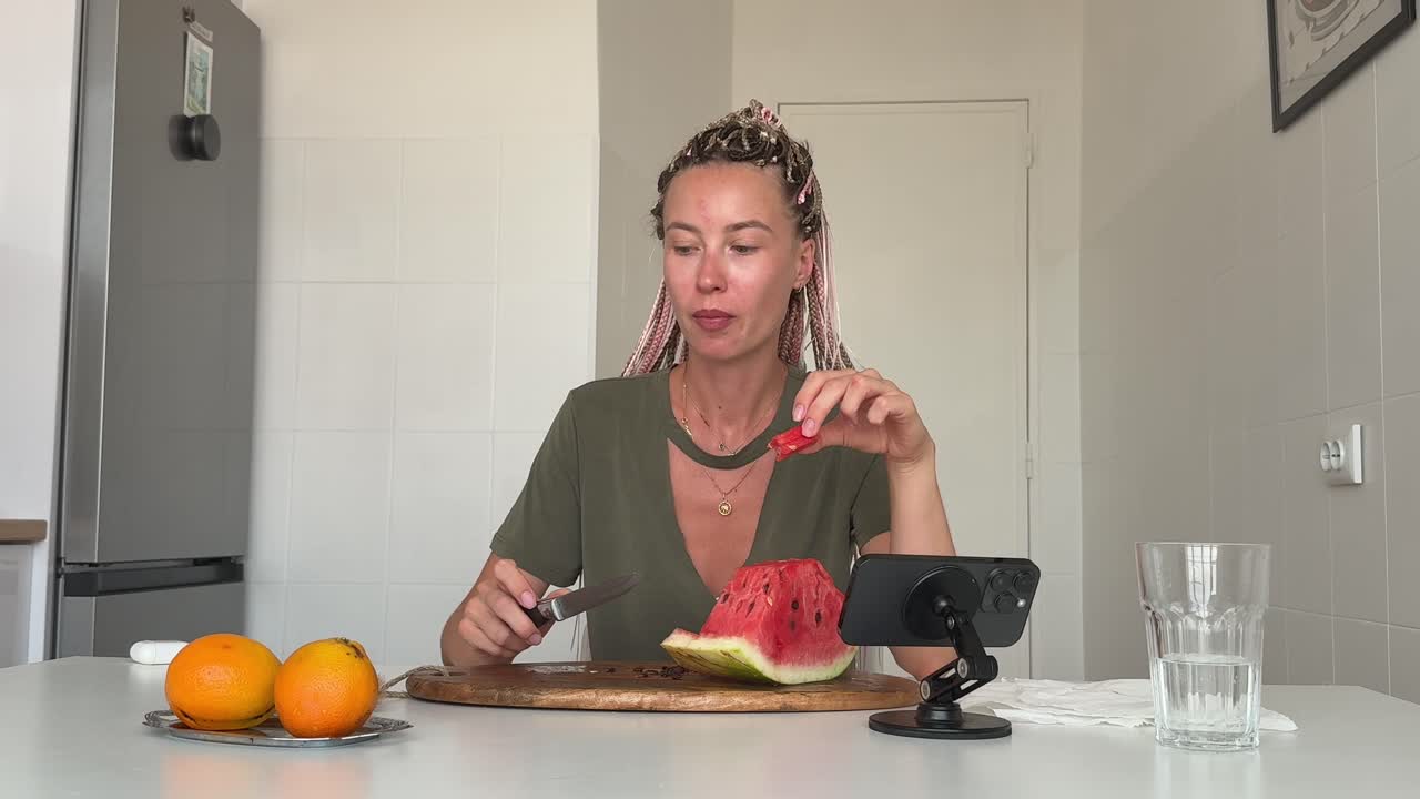 Young Woman Eating and Cutting Watermelon in a Bright Kitchen