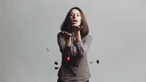 woman blowing confetti away. joyful party girl standing and blowing confetti and looking at camera