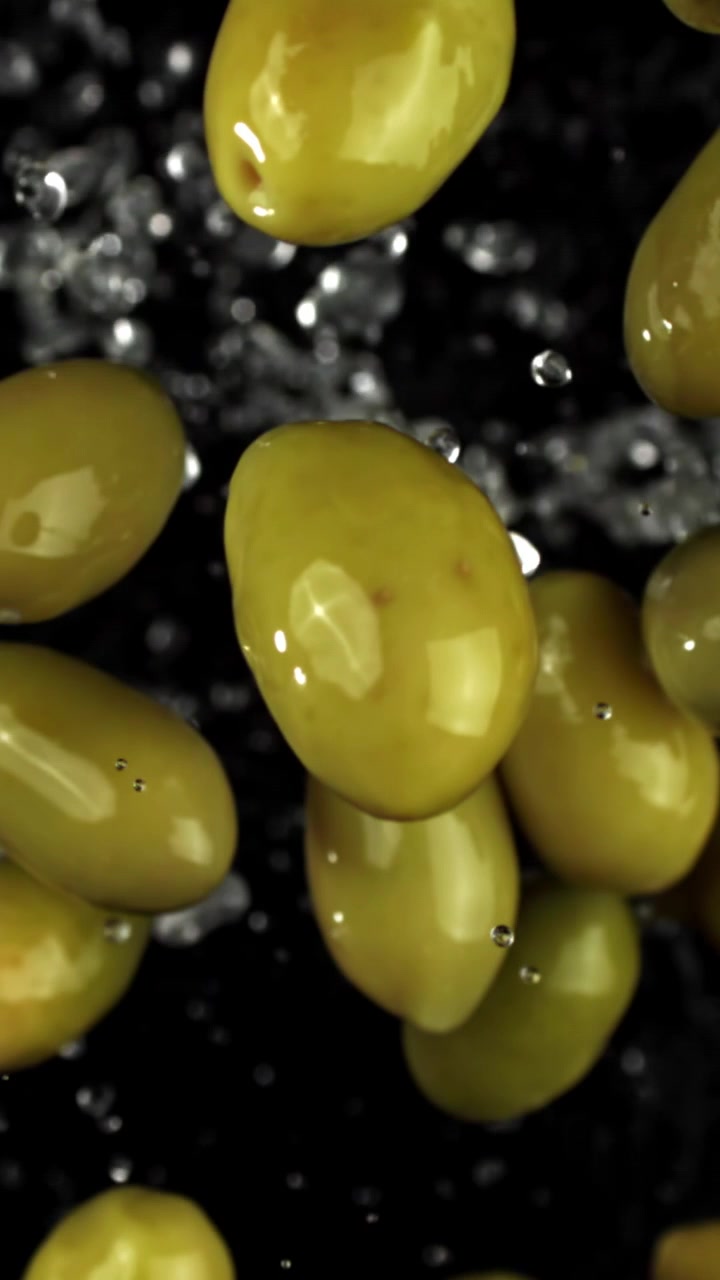 Super rallentatore di olive verdi che cadono con schizzi d'acqua
