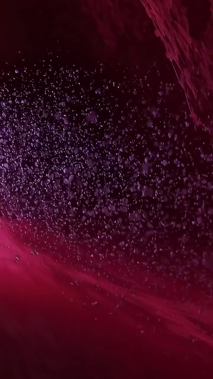 Video vertical: Panorámica mostrando una nube de gotas y grandes orbes flotando en cristal, revelando una pared texturizada