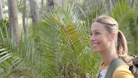 a young caucasian woman smiles while exploring a lush outdoor setting with copy space