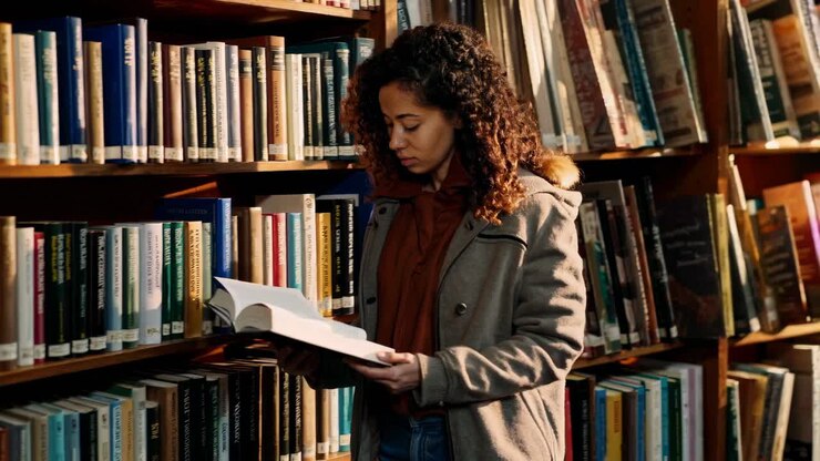 Una donna legge un libro in una biblioteca, ripresa in un mezzo busto